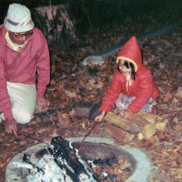 Shari as a child at a campfire with her dad and brother